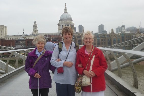 Two students with their guide walking on the Millennium bridge in London